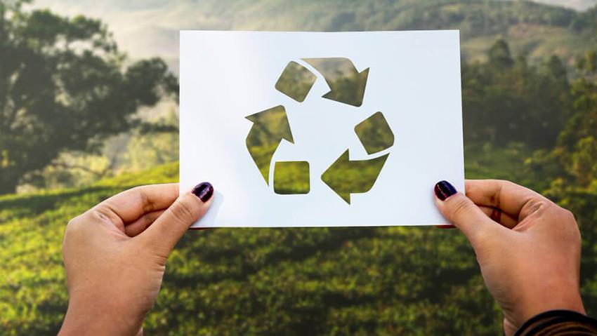 Une femme tient une pancarte avec le symbole du recyclage