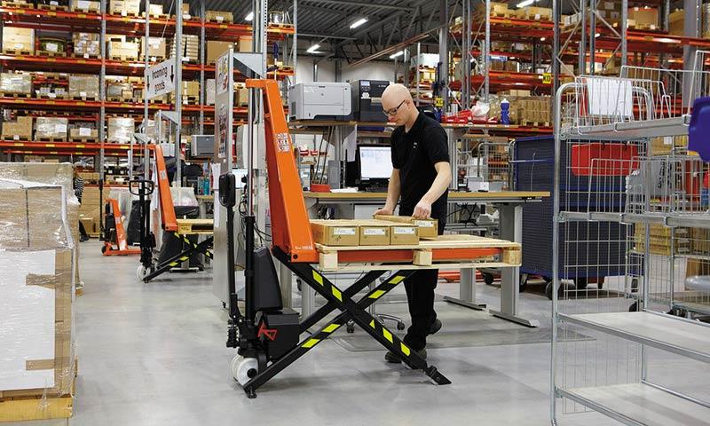 Un homme charge des marchandises sur un transpalette à ciseaux